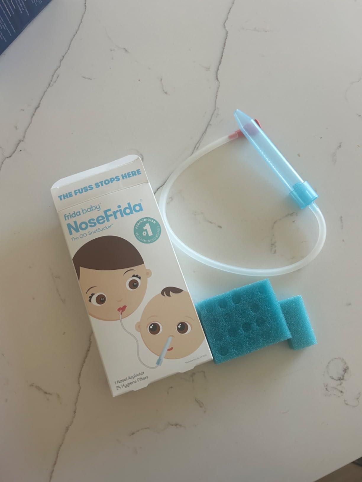 NoseFrida manual nasal aspirator parts laid flat on a wooden table